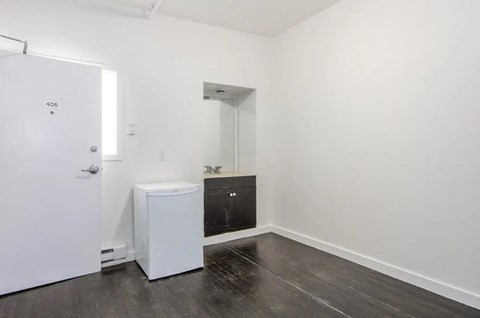 A white door with the number 405 on it is on the left of a room with a white fridge and a black oven.