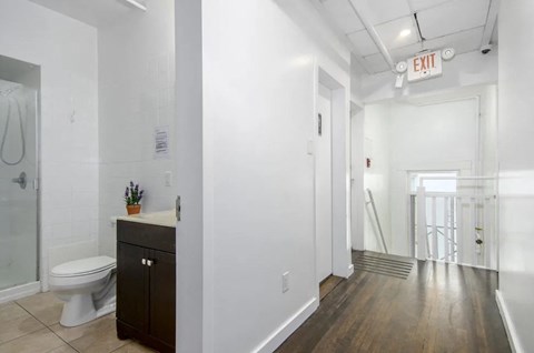 A white bathroom with a toilet, sink, and a wooden floor.