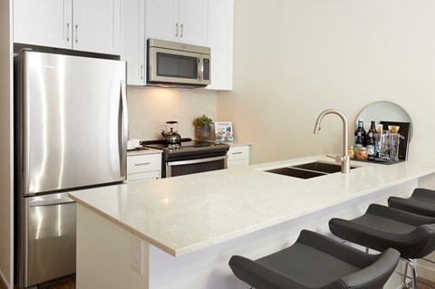 a kitchen with a white counter top and a stainless steel refrigerator