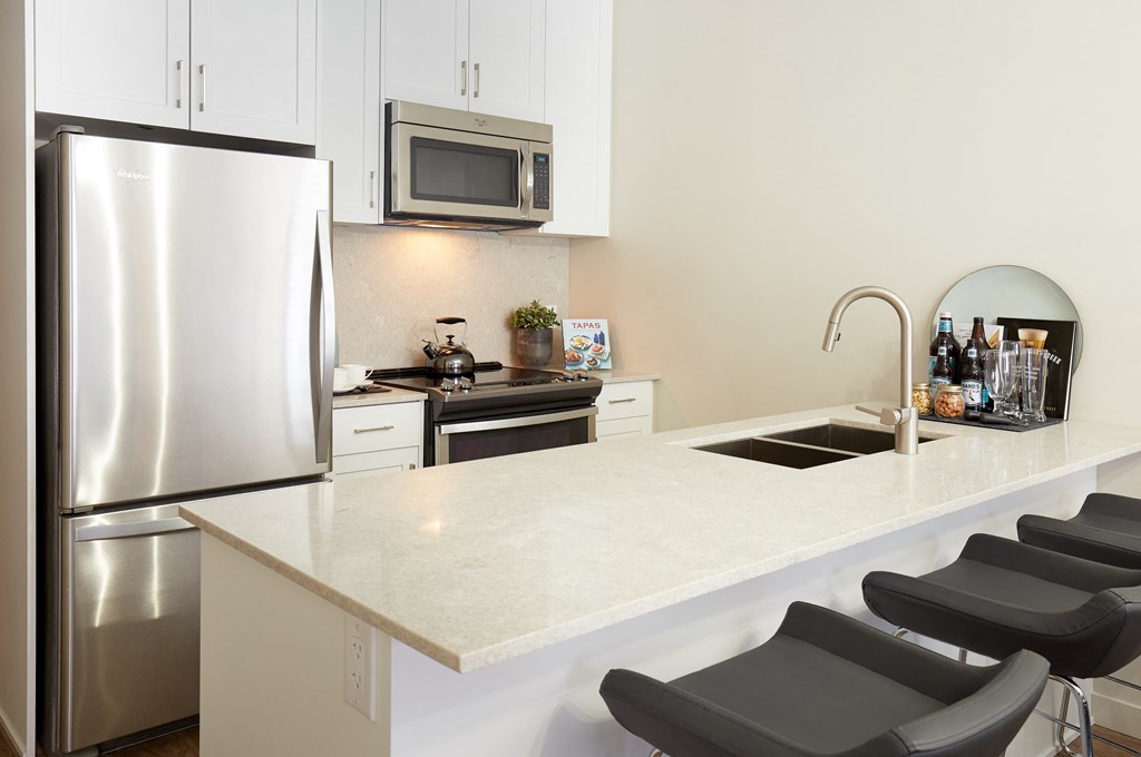 a kitchen with a white counter top and a stainless steel refrigerator
