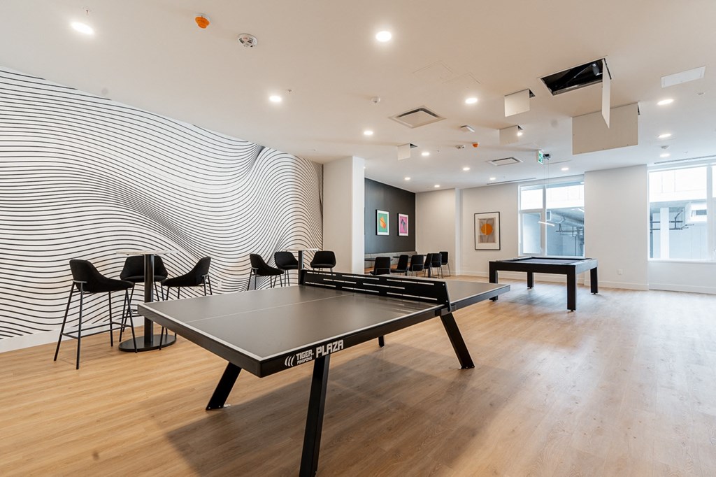 two ping pong tables in a room with chairs and a wall with