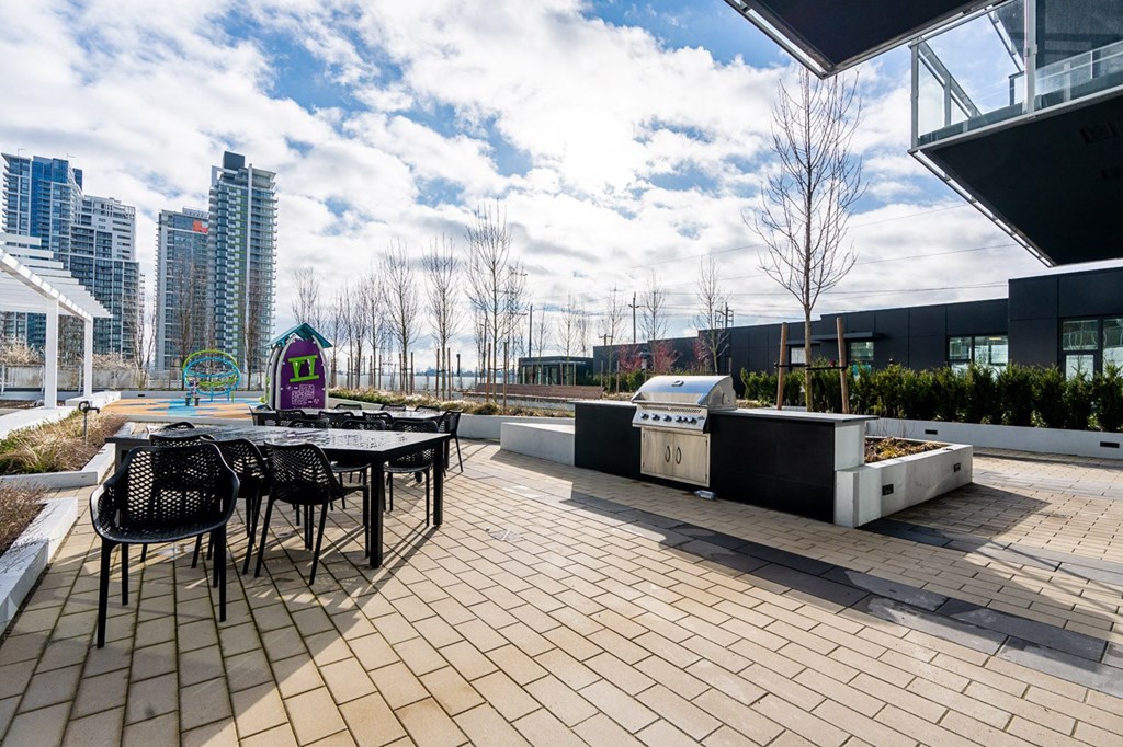 a patio with a table and chairs and a barbecue grill