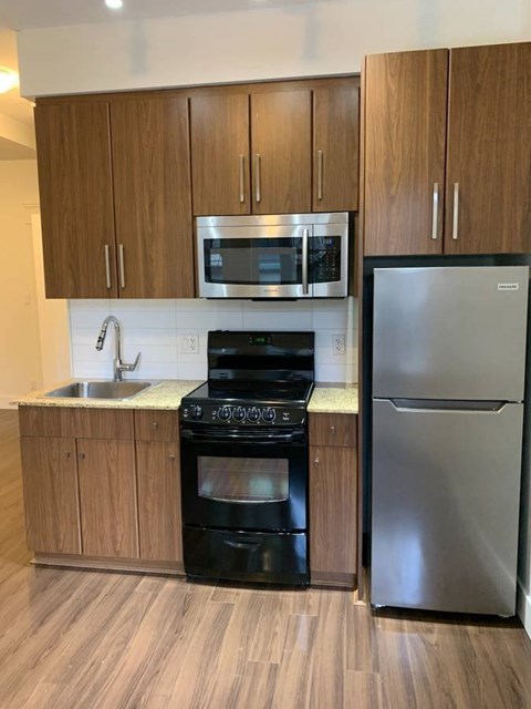 A kitchen with a stainless steel refrigerator and black oven.
