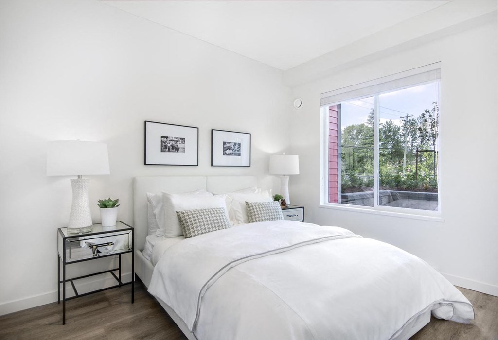 a white bedroom with a large bed and a window