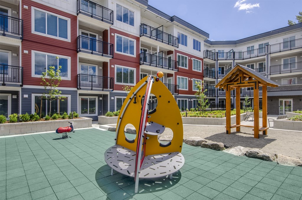 a playground at an apartment complex with a yellow swing set