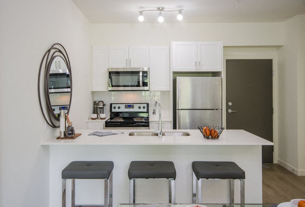 a white kitchen with three stools in front of a counter top
