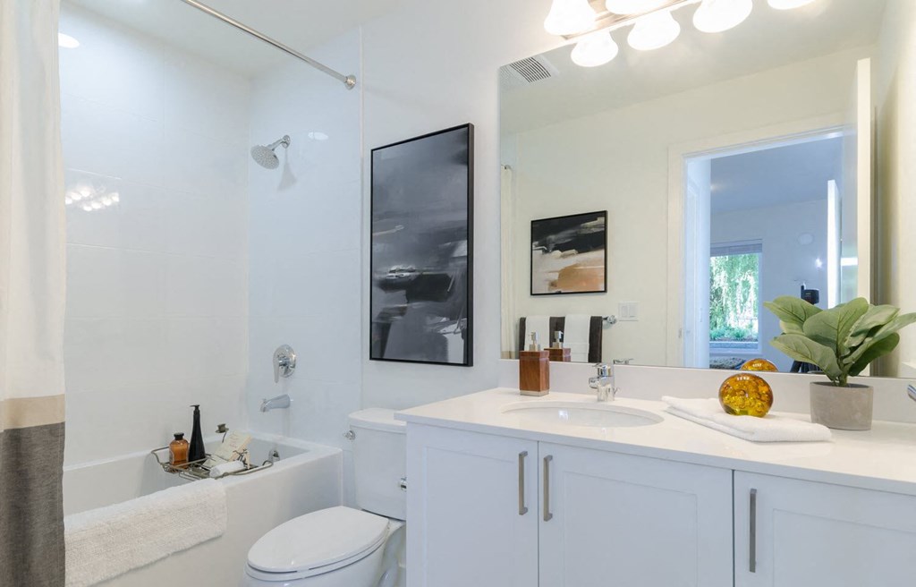 a white bathroom with a large mirror and a white sink and toilet