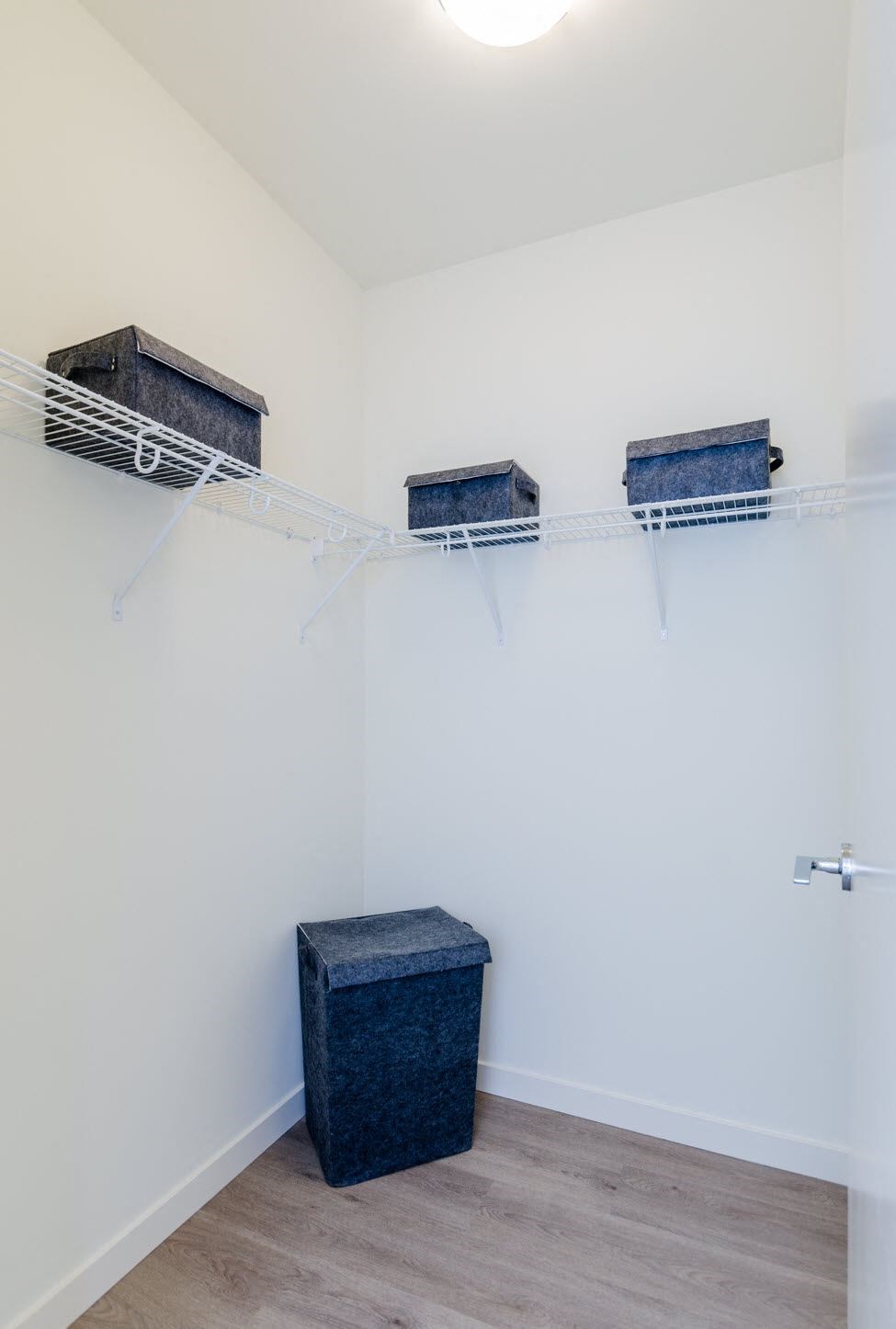 a closet with three shelves and a stool in it