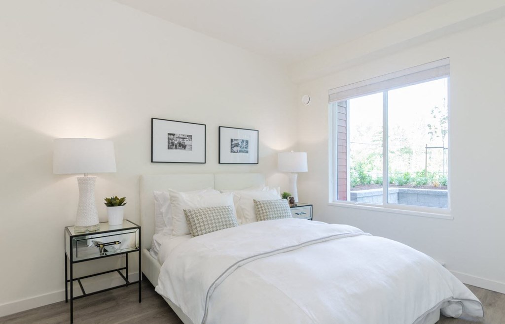a white bedroom with a large bed and a window