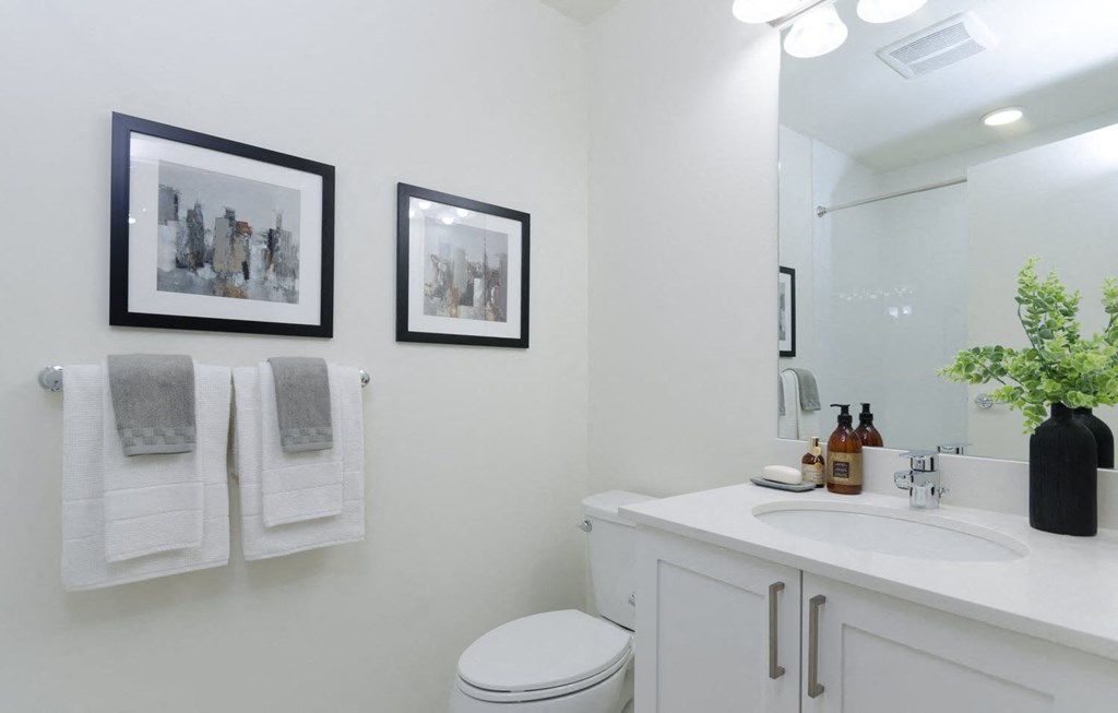 a white bathroom with pictures on the wall and a sink and toilet