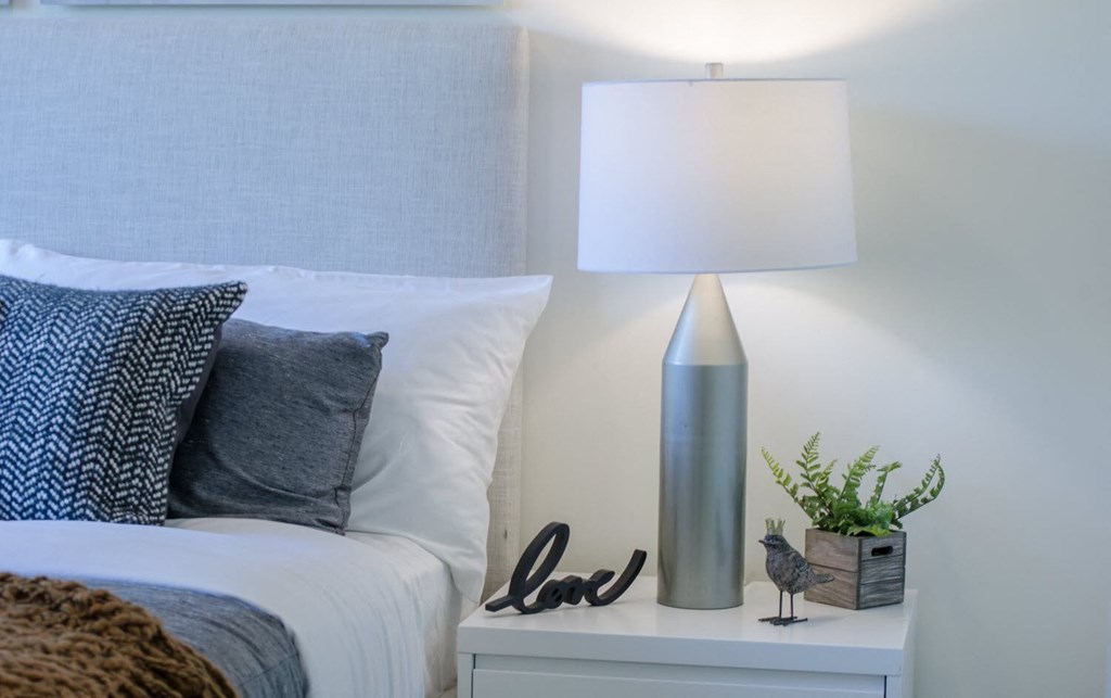 a bedroom with a bed and a lamp on a night stand
