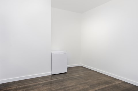 A white refrigerator sits in a room with wooden floors.