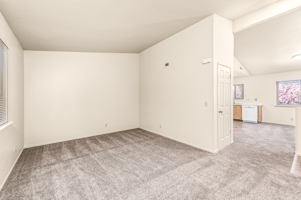Living room and kitchen of an apartment with carpeting and white walls at Meadowview Apartments, Santa Rosa, CA
