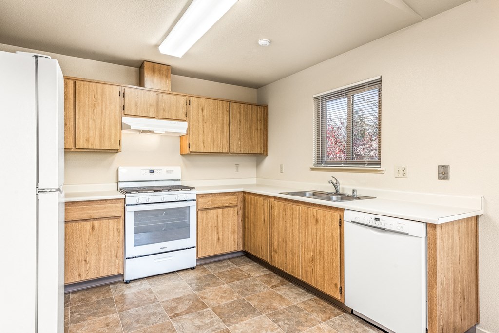 Kitchen with white appliances and wooden cabinets at Meadowview Apartments, Santa Rosa, CA