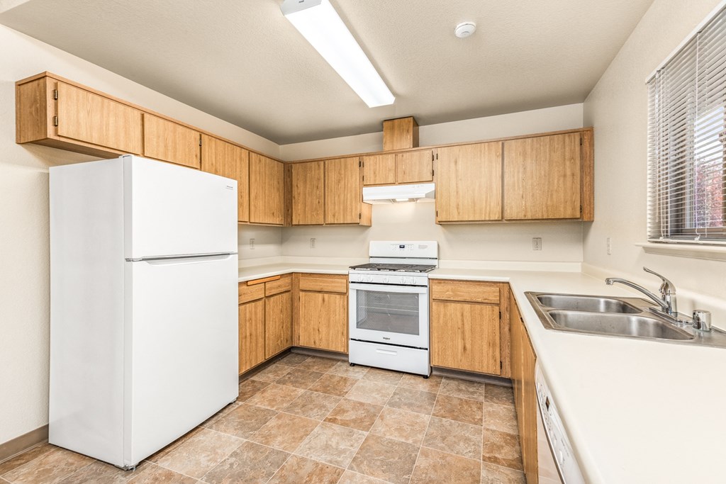 Kitchen with white appliances and wooden cabinets at Meadowview Apartments, Santa Rosa, CA