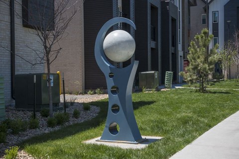 Outdoor sculpture in lawn area in front of townhomes.