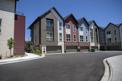 Outdoor view of townhomes with paved roads and sidewalk area.