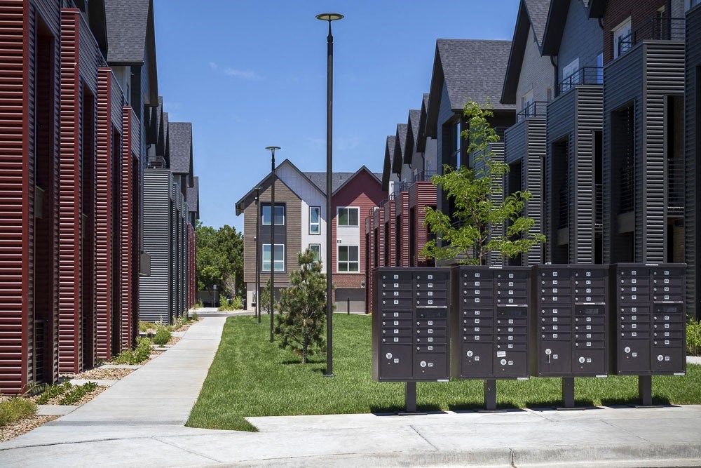 Outdoor view of townhomes with mailboxes and open green space between tow rows of townhomes.