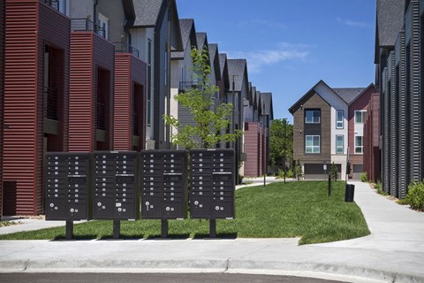 Outdoor view of townhomes with mailboxes and open green space between tow rows of townhomes.