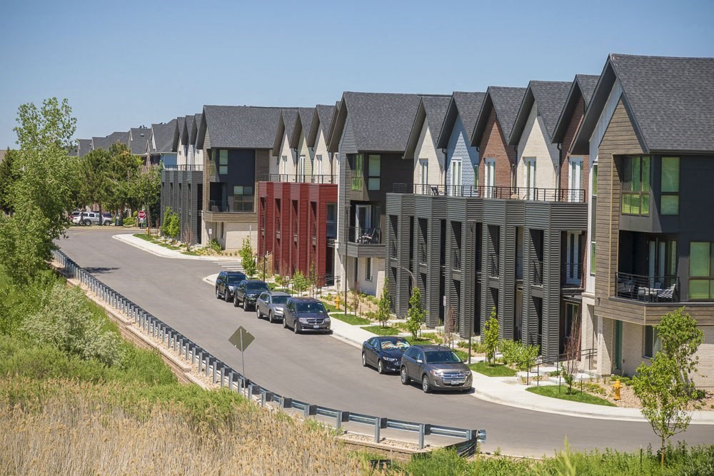 Outdoor view of townhomes with paved road and cars parked on the street.