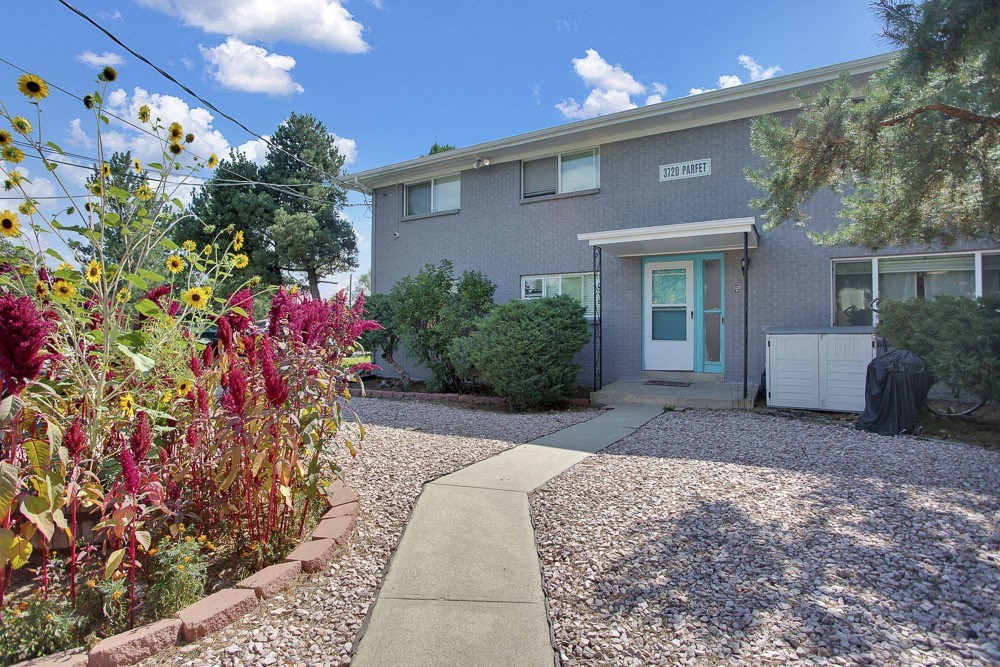 sidewalk path leading up to a townhome building with a flower bed on the left