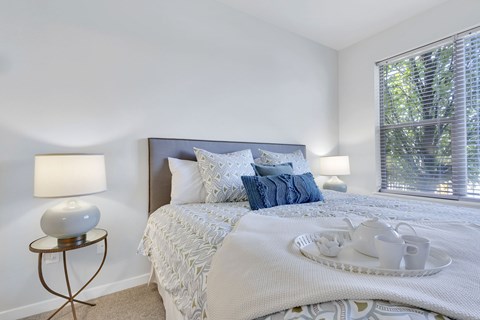 A bedroom with a bed, nightstand, and window.