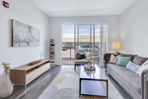 A living room with a grey couch, a coffee table, and a painting on the wall.