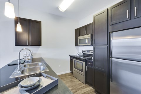 A modern kitchen with dark wood cabinets and stainless steel appliances.