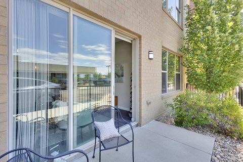 A patio with a chair and table outside a house.