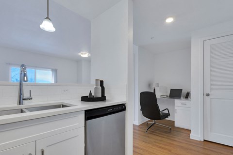 A modern kitchen with a black chair and a dishwasher.