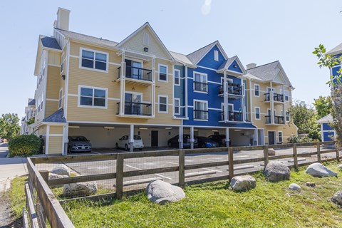 A large apartment building with multiple balconies and a parking area in front.