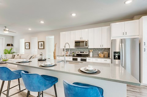 an open kitchen and living room with blue chairs and a counter