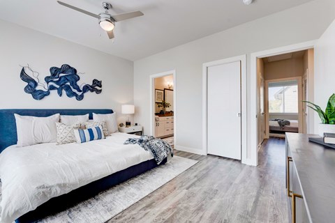 Apartment bedroom with wood floor, large bed and entry to the bathroom and closet.