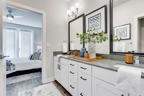 Townhome bathroom with dual sinks, large cabinet space, wood floors and entry to the bedroom.