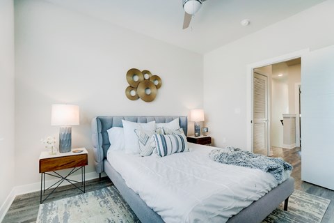 Townhome bedroom with wood floors, large bed, night stand, and entry to bathroom.
