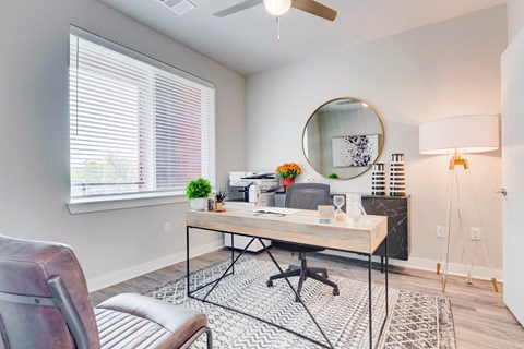 Townhome office room with desk, ceiling fan and large window.