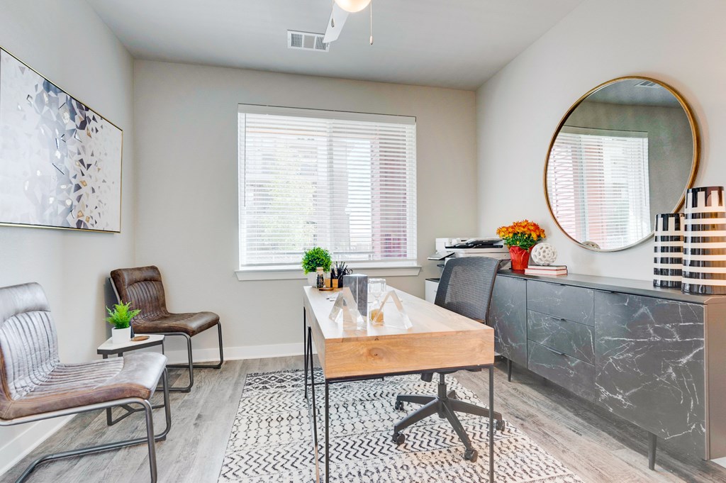 Townhome office room with desk, ceiling fan and large window.