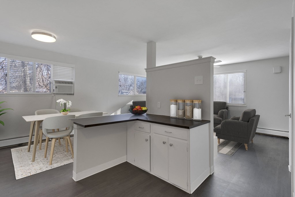kitchen view with an L shapped counter top and a dining space to the left and a view of the living room to the right