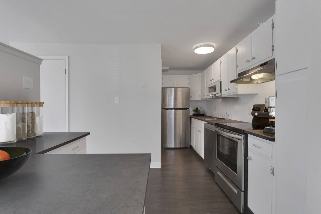 kitchen view with a long counter space to the right with an oven, stope top and refrigerator plus lots of cabinet space