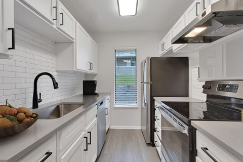 a kitchen with white cabinets and stainless steel appliances and a window