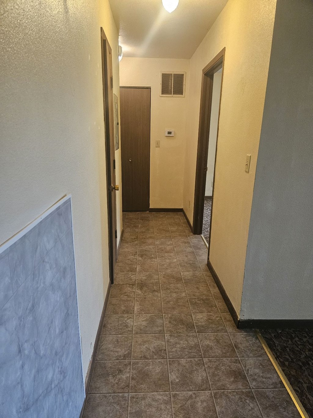A hallway with a brown door and a white wall.