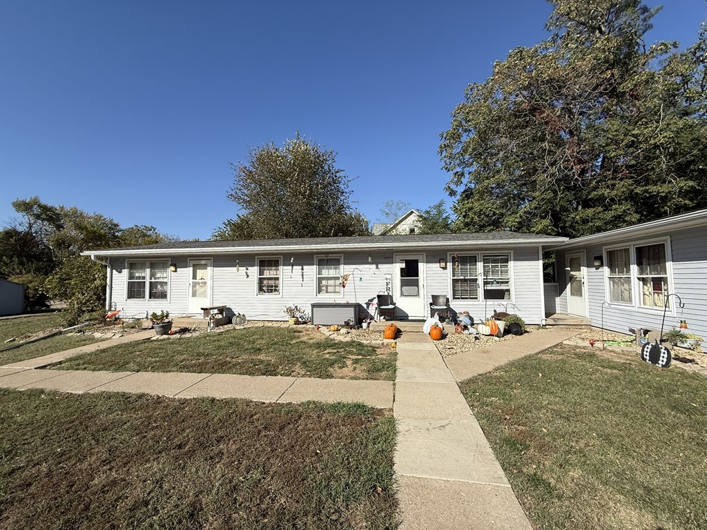 A house with a white exterior and a grey roof with a small front yard.