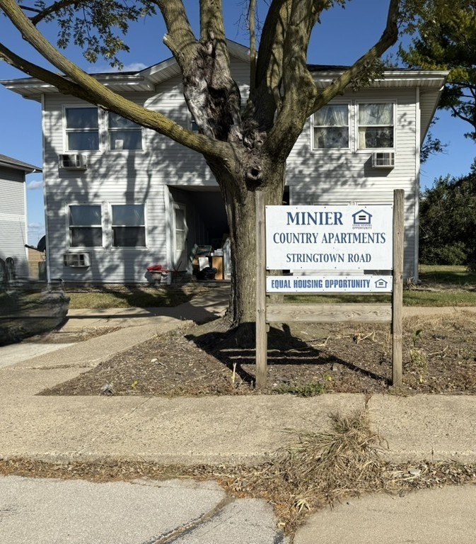 A sign for Minier Country Apartments stands in front of a building.