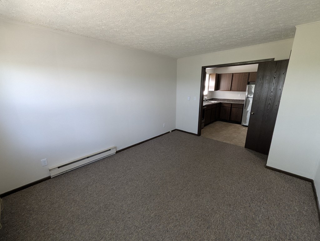 A room with a carpeted floor and a door leading to another room.