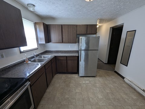 A kitchen with a refrigerator, sink, and cabinets.