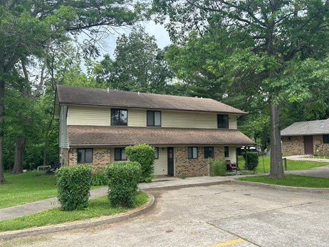 A house with a driveway and trees in the background.