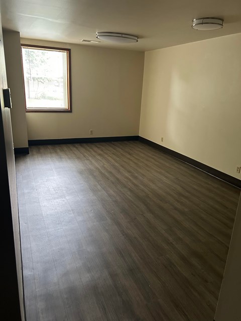 A room with a window and a wooden floor.
