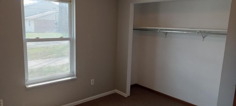 A room with a window and a coat rack.