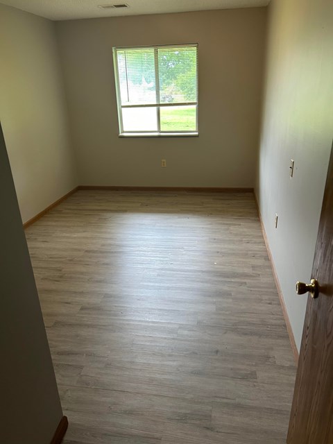 A room with a window and wooden flooring.