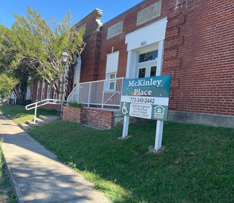 A sign for McKinley Place stands in front of a brick building.